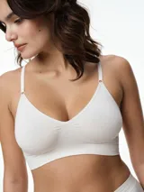 Bralette seamless de microfibra, color blanco, con diseño de escote en V, sin relleno y sin aros. Cuenta con breteles finos ajustables y una banda elástica inferior con logo grabado.