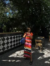 Vestido largo de tejido de punto, con rayas horizontales en tonos tierra, azul y blanco. Presenta cuello redondo, mangas cortas caídas y aberturas laterales en el ruedo.