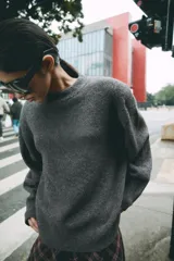 Sweater de punto color verde oscuro, con cuello redondo, manga larga y hombreras marcadas.