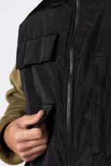 Campera de polar con recortes en tela técnica tipo sire en la parte superior frontal. Presenta cierre frontal completo, cuello alto y bolsillos funcionales en el pecho. Diseño bicolor en tonos verde oliva y negro con logo de la marca en el pecho.