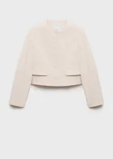 Chaqueta corta de cuello redondo y manga larga, con cierre frontal de botones y dos bolsillos laterales con solapa. Presenta un diseño recto y estructurado.