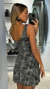 Vestido corto de fiesta con escote redondo y sin mangas, confeccionado en tejido de lurex con un diseño geométrico brillante. Presenta un corte evasé que aporta movimiento a la falda.