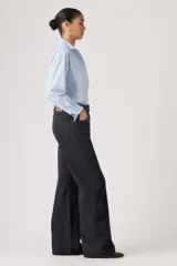 Jean de corte loose boot, tiro medio, color negro, con diseño de cinco bolsillos y cierre frontal con botón y cremallera.
