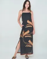 Vestido largo negro de lino con escote cuadrado, tirantes finos regulables y tajo lateral en la falda. Presenta un estampado de palmeras en tonos tierra y beige, y cuenta con bolsillos laterales.