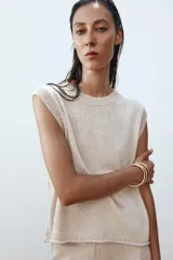 Top de punto color crema, de cuello redondo y sin mangas.