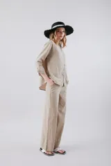 Pantalón de vestir color beige, de corte recto y tiro alto, con bolsillos laterales y cierre frontal con botón y cremallera.