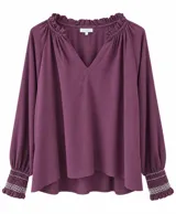 Blusa color bordó, de manga larga abullonada con puños fruncidos y detalles de bordado blanco, escote en V con volados en el cuello y diseño holgado.