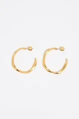 Pendientes de aro maxi con diseño irregular y acabado metálico mate en color dorado. Presentan una estructura retorcida y cierre de tuerca.