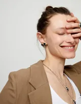 Par de aros plateados con cristal facetado grisáceo de forma ovalada.