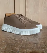 Zapatillas urbanas de cuero color marrón con textura granulada, cordones al tono y suela de plataforma dentada en color blanco.