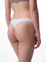 Bombacha tipo colaless de tiro medio, confeccionada en algodón con elastano. Presenta un diseño liso en color beige con terminaciones de bies elástico en contraste blanco y negro en la cintura y los bordes de las piernas.