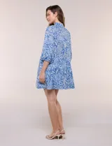 Vestido corto camisero de Elan, con diseño estampado en tonos de azul, cuello camisero clásico, mangas 3/4 abullonadas con elástico en los puños y falda con volantes fruncidos.