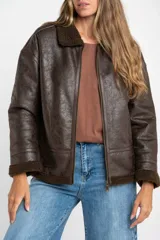 Campera tipo gamulán de corte oversize, color marrón oscuro con efecto cuero envejecido. Presenta cuello solapa, puños y ruedo con forro de corderito sintético en tono marrón oscuro. Cuenta con cierre frontal completo y detalles de costuras reforzadas.