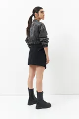 Minifalda de jean celeste con corte asimétrico, bolsillos de parche con solapa y tiras ajustables con hebillas en los laterales.