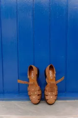 Sandalias de cuero vacuno color negro, estilo cangrejera, con diseño cerrado de tiras entrelazadas, tachas metálicas decorativas, tira con hebilla lateral ajustable y taco bajo.
