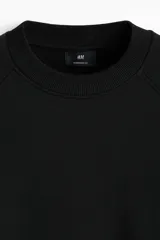 Buzo negro de tejido liviano con mezcla de algodón y viscosa, manga raglán y cuello redondo. Puños y bajo acanalados. Corte oversized para una silueta holgada.