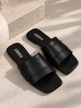 Sandalias planas de color negro con tira ancha acolchada y diseño de punta cuadrada.