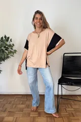 Remerón de manga corta, color beige claro, con bloques de color negro en las mangas. Presenta cuello redondo y un calce holgado.