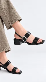 Sandalia de cuero color beige con taco cuadrado de 4 cm, tiras delanteras, tira ajustable con hebilla metálica dorada y tira elástica trasera.
