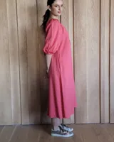 Vestido negro de corte amplio, con escote redondo fruncido y cordón ajustable, mangas abullonadas de tres cuartos y largo midi.