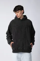 Buzo canguro de frisa gruesa con capucha, diseño oversize y acabado con efecto gastado. Presenta recortes horizontales en el frente y puños con elástico.