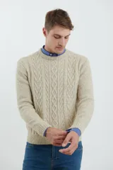 Sweater de tejido de punto color beige claro, con diseño de trenzas (aranes) en el frente y mangas de punto liso. Tiene cuello redondo.