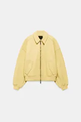 Cazadora tipo bomber de corte oversize confeccionada en piel 100% color amarillo pastel. Presenta cuello clásico, cierre frontal con cremallera metálica, bolsillos delanteros con solapa y acabados en tejido rib en puños y ruedo.