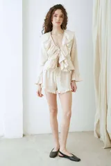 Blusa de voile color beige, de manga larga, con volados en el escote en V y tirantes frontales para atar.
