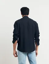 Camisa de cuello mao y manga larga, confeccionada en una mezcla de lino y algodón. Presenta un diseño de corte recto con botones en tono natural y un bolsillo pequeño en el pecho.