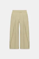 Pantalón de tiro medio color beige perteneciente a la colección ZW Collection, de corte ancho y recto, con detalle de pliegues frontales y cierre con cremallera y ganchos metálicos.