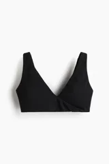 Top deportivo negro para yoga, de tejido funcional con efecto segunda piel y alta elasticidad gracias a la tecnología Lycra® Sport. Diseño con breteles anchos, escote en V profundo y detalle cruzado/girado en el frente. Incluye copas forradas con relleno extraíble.