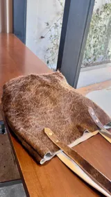 Bolso tipo tote de cuero con pelo color marrón y blanco, con manijas de cuero crudo.