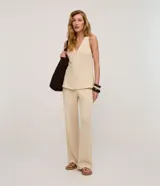 Chaleco de punto color beige claro, con cuello en V y cierre frontal de botones. El tejido presenta un patrón texturizado de pequeños puntos.