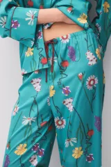 Pijama de satén turquesa con estampado floral multicolor, compuesto por una camisa de manga larga con botones y cuello camisero, y pantalón largo a juego.