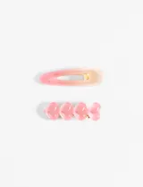 Set de dos clips para el pelo: uno tipo hebilla con degradé de rosa a beige y otro con cuatro corazones rosas.