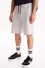 Bermuda de felpa sin friza color gris melange, con cintura elastizada y cordón ajustable negro. Cuenta con bolsillos laterales con cierre.