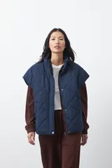 Chaleco acolchado de nylon con diseño capitoneado, cuello alto y cierre frontal con botones a presión. Presenta un calce amplio y versátil.