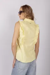 Blusa celeste sin mangas con cuello camisero y volados en los hombros.