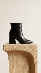 Bota de caña media confeccionada en cuero negro, con diseño de líneas simples, punta cuadrada y taco cuadrado firme.