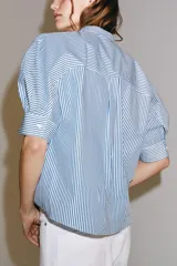 Camisa de algodón con estampado de rayas verticales azules y blancas. Presenta cuello mao, cierre frontal con botones a contraste y mangas cortas abullonadas con puños rectos.