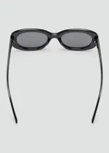 Lentes de sol con montura ovalada de pasta negra y cristales oscuros.