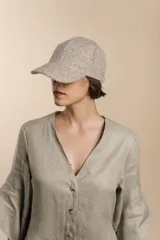 Gorra con visera confeccionada en lana fina sin teñir, con un sutil patrón de tejido en espiga.