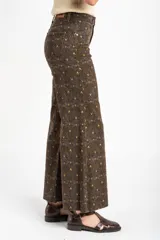 Jean flared wide leg de tiro medio con estampado geométrico en tonos marrón, verde militar y amarillo.