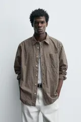 Camisa relaxed fit de algodón con estampado de cuadros en tonos marrón y beige. Cuenta con cuello solapa, manga larga con puño abotonado, bolsillo plastrón en el pecho y cierre frontal de botonadura.