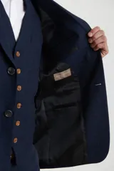 Saco azul oscuro de corte clásico, con solapa de muesca, cierre de dos botones, tres bolsillos delanteros y puños con cuatro botones.