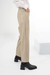 Pantalón de vestir color beige, de corte recto, con bolsillos laterales y traseros. Se ajusta a la cintura con cinturón de cuero marrón.