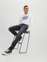 Jean de corte slim con tiro bajo, confeccionado en denim de color negro con efecto lavado. Presenta diseño clásico de cinco bolsillos y cierre frontal con botón.