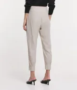 Pantalón negro de lino, corte carrot, con cintura ancha y pliegues en el bajo.