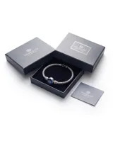 Pulsera de plata con diseño trenzado y una piedra circonia redonda facetada en color azul zafiro en el centro.