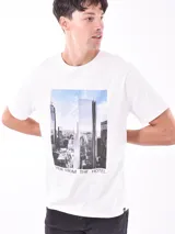 Remera color arena con cuello redondo y estampado pequeño en el pecho.